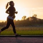 Woman running on track at sunset.